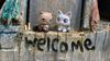 Photo of custom Littlest Pet Shop figures of Ari and Cameron on a wooden sign that says 'welcome' 